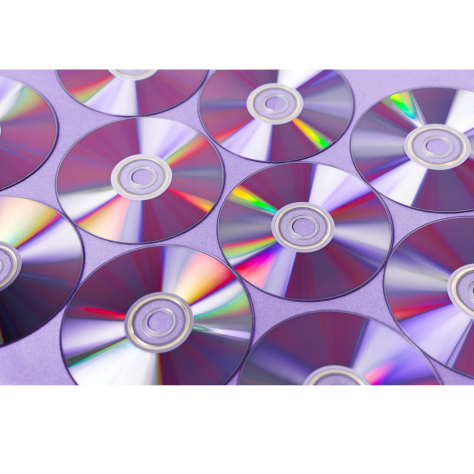 Multiple CDs laid out next to each other on a purple table.