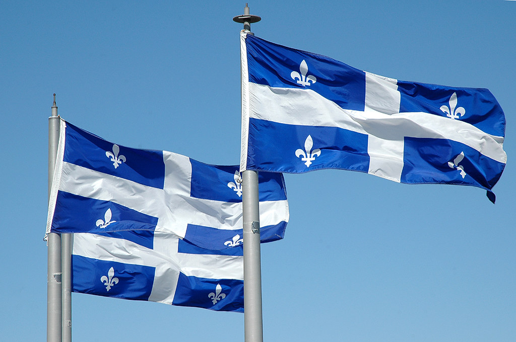 Three Quebec flags flutter in the wind.