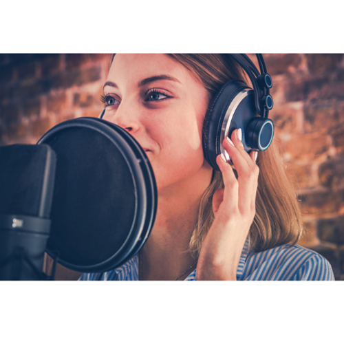 a woman wearing headphones speaks into a large microphone.