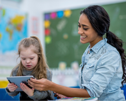 a teacher and young student look at a tablet together.