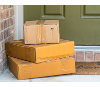a stack of packages sits outside the door to a house.