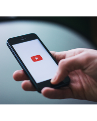close up of a hand holding a phone with the YouTube red play icon.